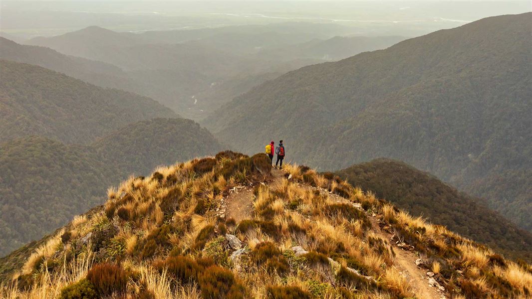 Two people standing on top of a peak looking out